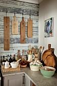 Nostalgic bowls and cooking utensils on corner worksurface under chopping boards hung on wall