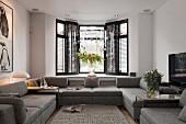 Grey, modern sofa combination in front of bay window and Christmas arrangement suspended from ceiling