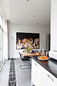 View along kitchen counter to dining area with cantilever chairs, large photo of party and heating grate in floor