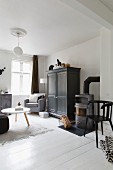Corner of monochrome living room; coffee table with white top and cupboard painted dark grey on white wooden floor