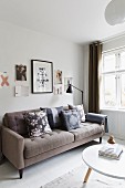 Beige, retro sofa with scatter cushions in various patterns below pictures on wall