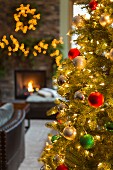 Golden leuchtender Weihnachtsbaum in Wohnzimmer mit offenem Kamin