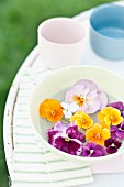 Pansies and violas floating in bowl on garden table