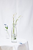 Lily of the valley in small pop bottle decorated with forget-me-not postage stamp