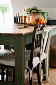 Chairs with carved backrests at rustic table; candlesticks and bowl of fruit on table