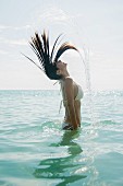 A young woman whipping her hair in the water