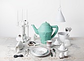 Table set with bizarre, white objets d'art and turquoise ceramic teapot