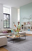 Coffee table with delicate frame and beige corner sofa in spacious, high-ceilinged interior