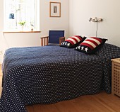 Blue bedspread and stars and stripes scatter cushions on double bed in Scandinavian bedroom