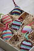 Striped, crocheted Easter eggs nestled in hay in box