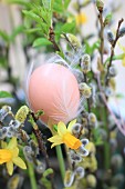 Hen's egg decorated with white feathers in Easter bouquet