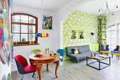 Colourful living area with patterned wallpaper in retro interior with antique dining table