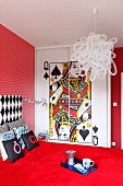 Bold, red bedroom with playing card motif on front of fitted wardrobes