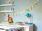 Selbstgenähte bunte Wimpelkette über Schreibtisch im Kinderzimmer