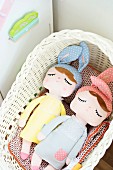 Fabric dolls with sleeping eyes and wearing bunny ears in wicker basket