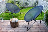 Modern outdoor easy chairs with grey string seats in small, fenced garden