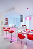 Bright red shell chairs and bar stools at white dining table and kitchen counter