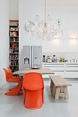 Dining area with orange classic chairs below Zettel'z lamp by Ingo Maurer in open-plan kitchen