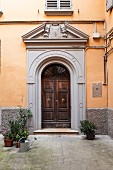 Entrance to traditional, Italian palazzo in courtyard with ochre façade and grey strip along base