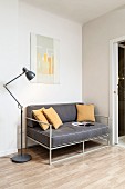Delicate, grey sofa with ochre scatter cushions and retro standard lamp in corner