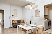 Small dining table, cantilever chairs and delicate, grey sofa in living area