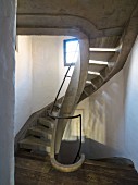 Concrete spiral staircase in renovated stairwell with patterns of light and shade
