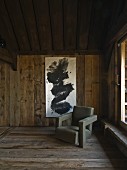 Extravagant armchair in front of modern, black and white artwork on wooden wall in rustic interior