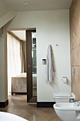 Bathroom with bidet, wall-mounted toilet and view into bedroom through open sliding door