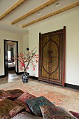 Elegant, silk cushions on couch, antique Moroccan door and floor vase on Persian rug