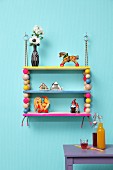 Colourful, hand-made shelves with wooden beads threaded on climbing ropes and decorated with vintage-style toys