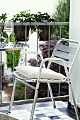 Stainless steel outdoor chairs with white cushion next to bistro table on balcony