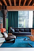 Sessel Wink Lounge Chair von Toshiyuki Kita und dunkelblaues Sofa in Loungebereich vor Glasfassade einer Loftwohnung