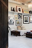 Couch with white throw below gallery of framed pictures in rustic interior
