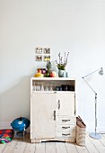 Crockery in white, half-height cabinet next to barbecue and standard lamp