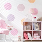 Half-height cabinet on castors in romantic, feminine interior with hand-crafted pattern made from pastel circles of wallpaper or gift wrap on wall