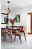 Poster and fifties-look sideboard in dining area with wooden chairs and wooden table with glass top