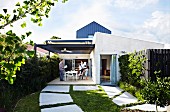 Large stepping stones in lawn leading to roofed terrace of Australian house