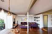 Open-plan, modern interior with exposed roof beams and purple sofa set in lounge area