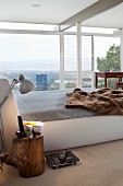 Box spring bed with fur blanket in modern bedroom with panoramic view