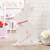 Hand-crafted, wooden Easter bunny in front of white brick wall