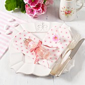 Silver cutlery on vintage plate decorated with napkin folded into heart and small bottle