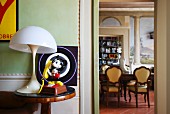 Mickey Mouse figurine and vintage lamp on side table; view into dining room with trompe l'oeil painting on wall