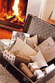 Open suitcase filled with gifts in front of open fire