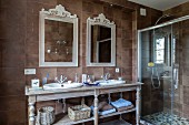 Vintage-style washstand with twin sinks and ornate mirrors next to glazed shower area