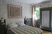 Doppelbett mit gestreiftem Überwurf, Schrank mit Türfüllung aus gerafftem Stoff im Schlafzimmer in Naturtönen