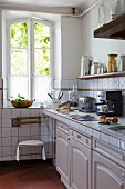 Provençal country-house kitchen with tiled worksurface and terracotta floor