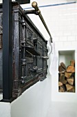 Antique kitchen stove with brass towel rail and firewood in niche in background