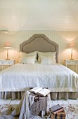 Grand double bed with curved headboard in country-house bedroom with pale wood panelling