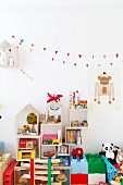 Toys stacked on floor and in cubic shelves on wall below bunting