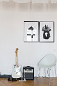 Black and white graphic artworks above shell chair, electric guitar andd amplifier